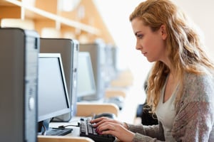 Cute student working with a computer in an IT room